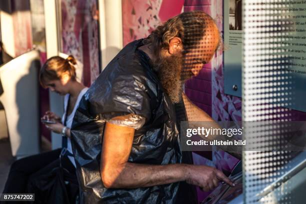 Deutschland Germany Berlin Obdachloser mit Plastiksack und mit Plastik verbundenen Füssen an einer Bushaltestelle am Potsdamer Platz.