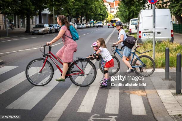 Deutschland Germany Berlin Mutter zieht Kinder mit Inline-Skatern über einen Zebrastreifen in Berlin-Pankow.