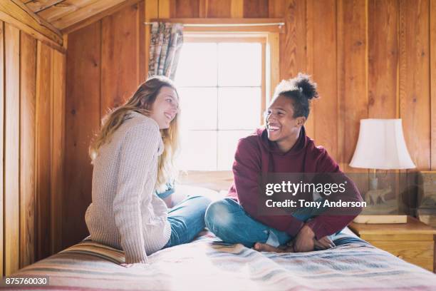 Teenage boy and girl sitting on bed in rustic cabin