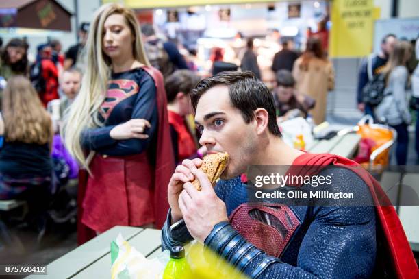 Supergirl cosplayer gives a Superman cosplayer a disaproving glance as he eats during the Birmingham MCM Comic Con held at NEC Arena on November 18,...