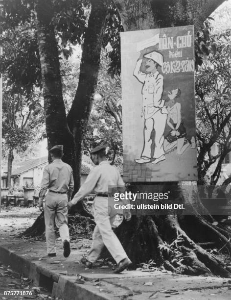 Ein Propagandaplakat in einer Ortschaft der Rhades im Hochland: es zeigt einen nordvietnamesischen Offizier, der einen Bauern in Ketten hält. Um 1963