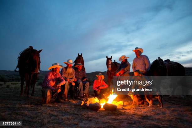 gruppe von cowboys und cowgirls teilen ein lagerfeuer in der dämmerung - kastanienfarben stock-fotos und bilder