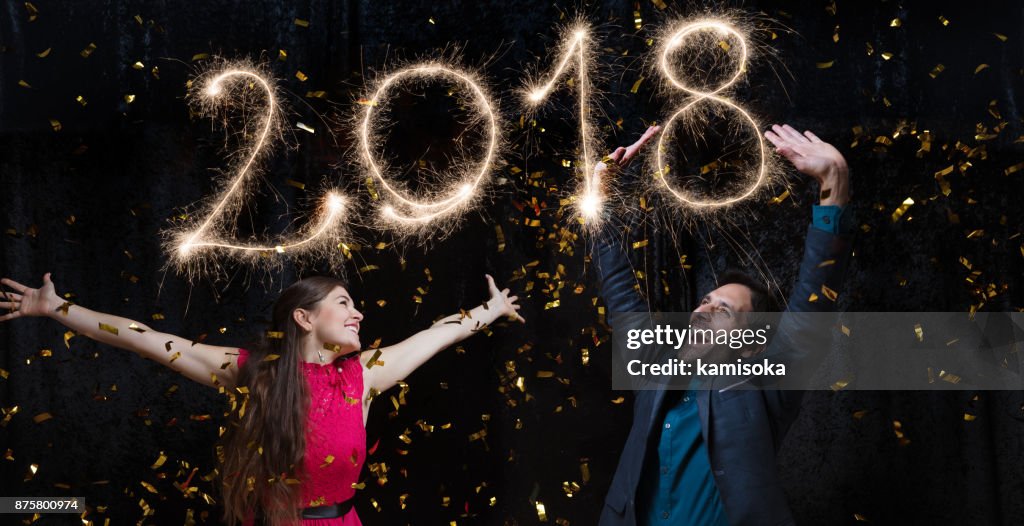 Beautiful couple celebrating New Year's Eve with sparkler 2018