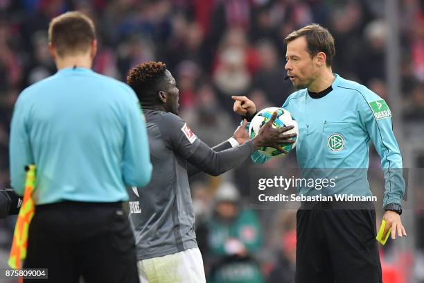 Referee Markus Schmidt argues with Daniel Opare of Augsburg during the Bundesliga match between FC Bayern Muenchen and FC Augsburg at Allianz Arena...