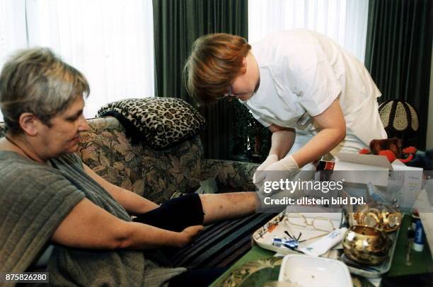 Pflegerin des Malteser Hilfsdienstes verbindet einer Patientin das Bein - 1997