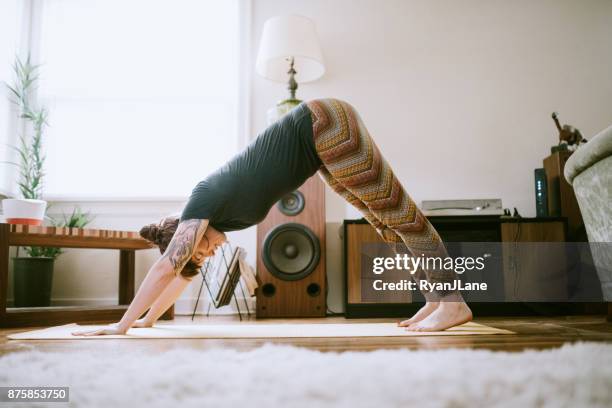 young adult woman at home practicing yoga - downward facing dog position stock pictures, royalty-free photos & images
