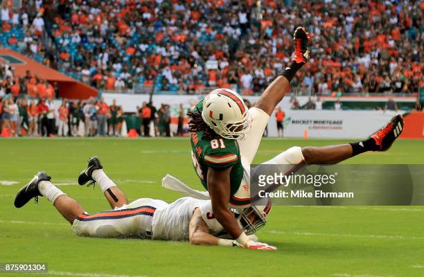 Darrell Langham of the Miami Hurricanes makes a catch over Quin Blanding of the Virginia Cavaliers during a game at Hard Rock Stadium on November 18,...