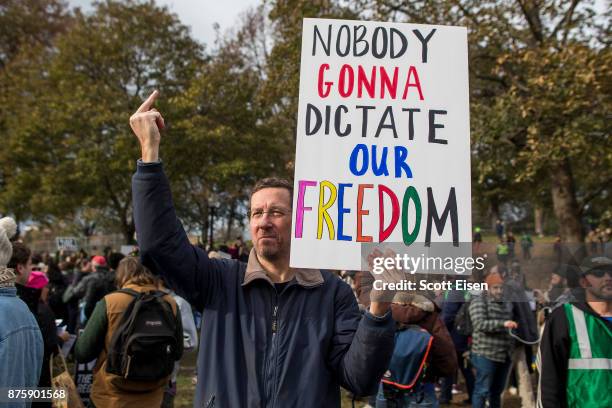 Counter protester of an Alt-Right organized free speech event holds up a sign and his middle finger on the Boston Common on November 18, 2017 in...