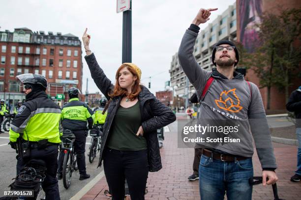 Woman and man hold up their middle fingers as participants of an Alt-Right organized free speech event walk past on November 18, 2017 in Boston,...