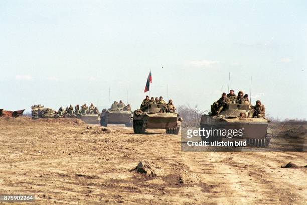 Krieg im Kaukasus: eine russische Panzerkolonne rollt durch eine öde Sandlandschaft der russischen Teilrepublik Tschetschenien. Soldaten sitzen auf...