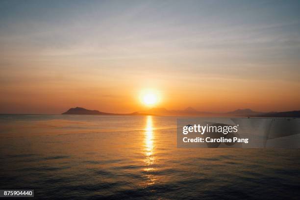 sunset, calm sea and mountains beyond the horizon as seen from the coast of ende, flores, indonesia. - caroline pang bildbanksfoton och bilder