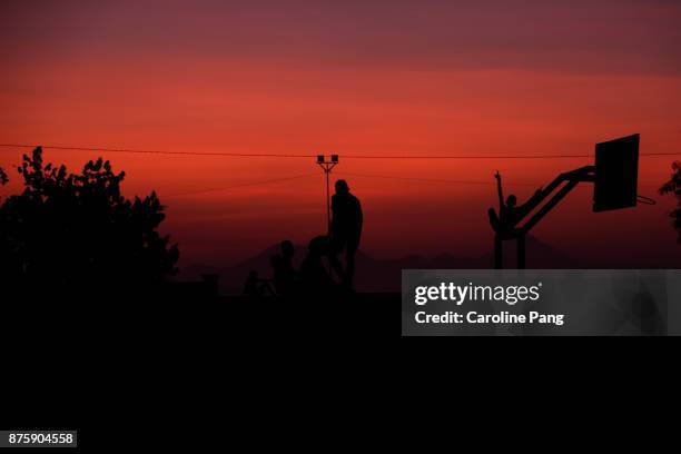 silhouette of people against the warm red sky of sunset in ende, flores indonesia. - caroline pang stock pictures, royalty-free photos & images