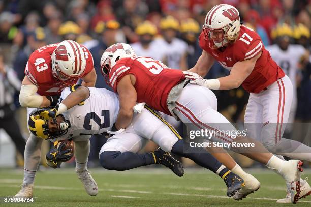 Chris Evans of the Michigan Wolverines is brought down by Ryan Connelly and T.J. Edwards of the Wisconsin Badgers during the fourth quarter of a game...