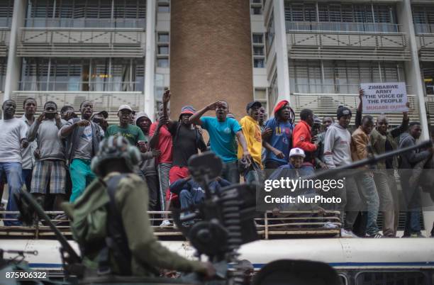 Protesters demanding President Robert Mugabe stand down, look up and cheer as an army helicopter flies over the crowd, as they gather in front of an...