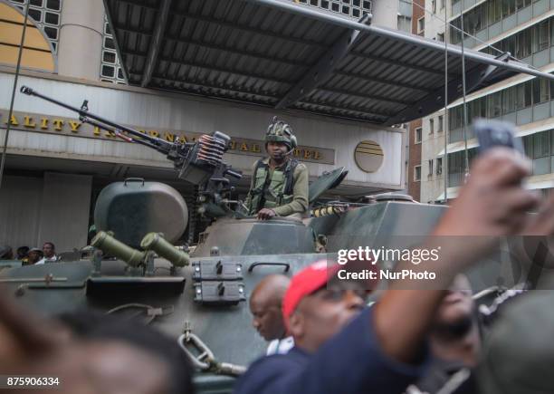 Protesters demanding President Robert Mugabe stand down, look up and cheer as an army helicopter flies over the crowd, as they gather in front of an...