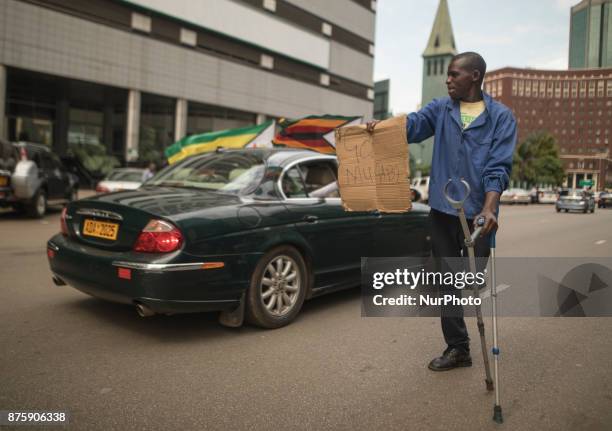 Protesters demanding President Robert Mugabe stand down, look up and cheer as an army helicopter flies over the crowd, as they gather in front of an...