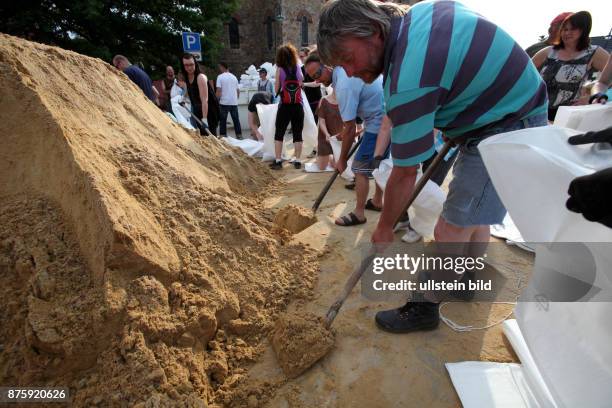 Magdeburg, Flutpegel ueber 7,20 m, Bürger füllen Sand in Sandsäcke zum Hochwasserschutz, Männer mit Schaufel
