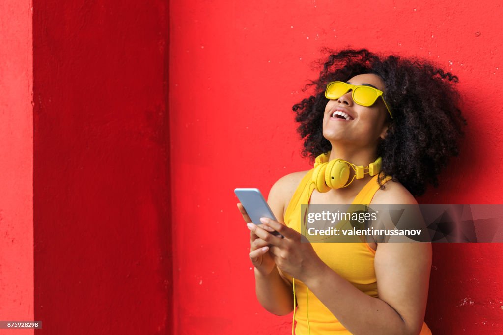 Smiling american-african woman listening music on smart phone