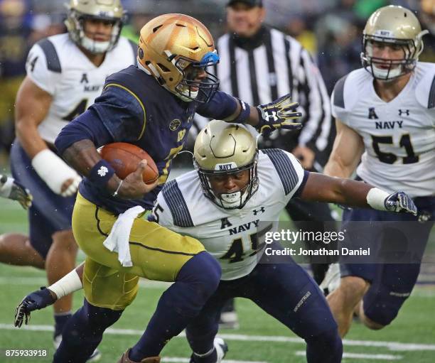 Brandon Wimbush of the Notre Dame Fighting Irish holds off D.J. Palmore of the Navy Midshipmen at Notre Dame Stadium on November 18, 2017 in South...