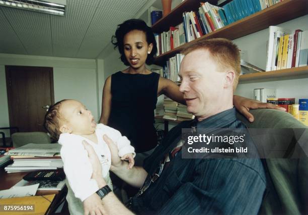 Christoph Matschie, SPD, Mitglied des Bundestages, D hält seinen Sohn Felix, während er im Büro am Schreibtisch sitzt. Seine Ehefrau Mitslal...