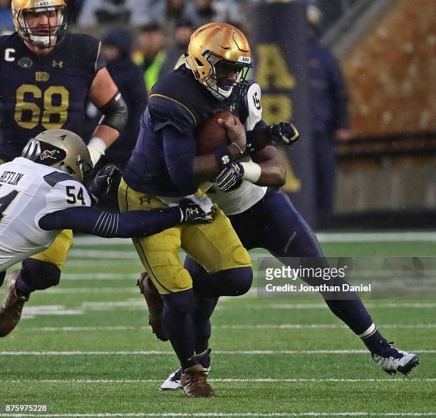 Brandon Wimbush of the Notre Dame Fighting Irish is tackled by Taylor Heflin against the Notre Dame Fighting Irish D.J. Palmore of the Navy...