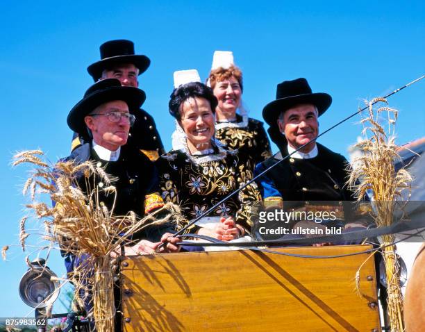Bretonische Familien auf geschmueckter Kutsche und in traditioneller bretonischer Tracht, die in der Landschaft Finistere nur noch zu festlichen...