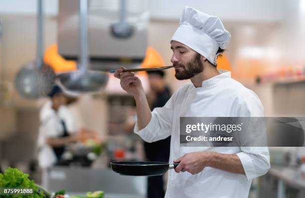 koch in einem restaurant verkostung eine sauce, die er gerade vorbereitet - chef smelling food stock-fotos und bilder