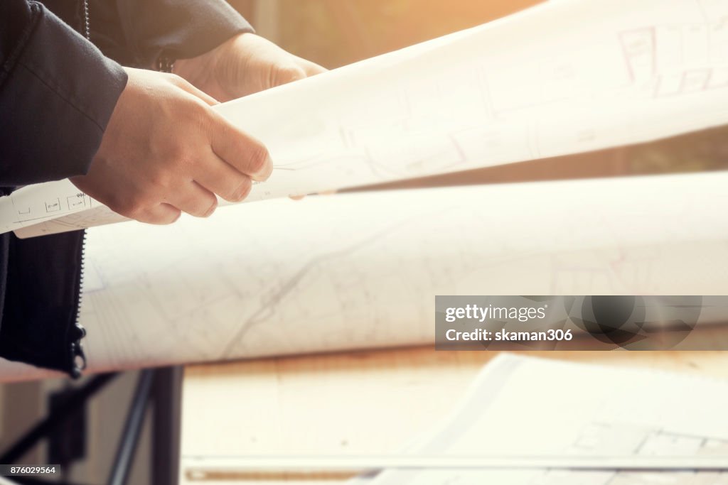 Close-up hand Of male Architect Drawing Blueprint on work space wooden table in office