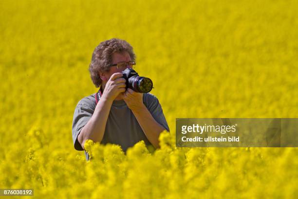 Ludwig Werle Fotograf stehend in gelb bluehendem Rapsfeld rechts sehend