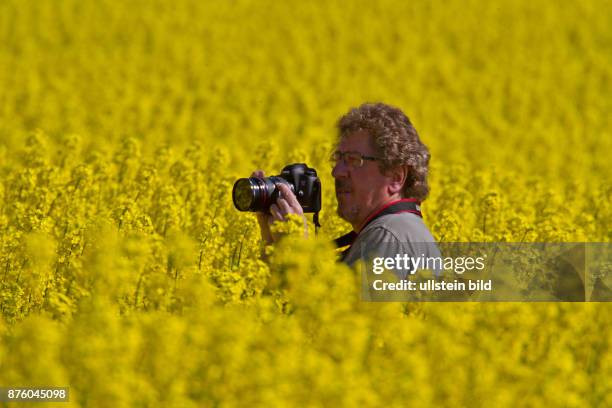 Ludwig Werle Fotograf stehend in gelb bluehendem Rapsfeld links sehend