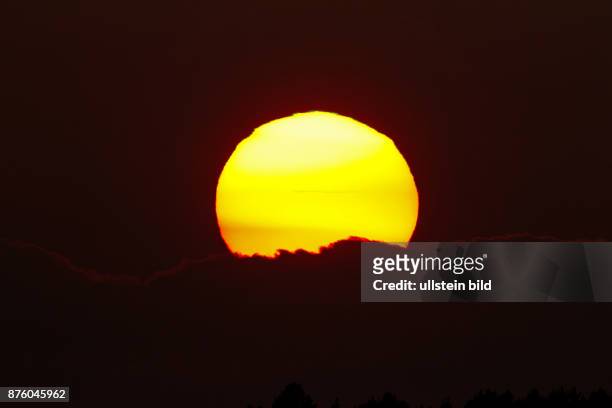 Sonnenuntergang gelbliche Sonne vor roetlichem Abendhimmel mit Wolken