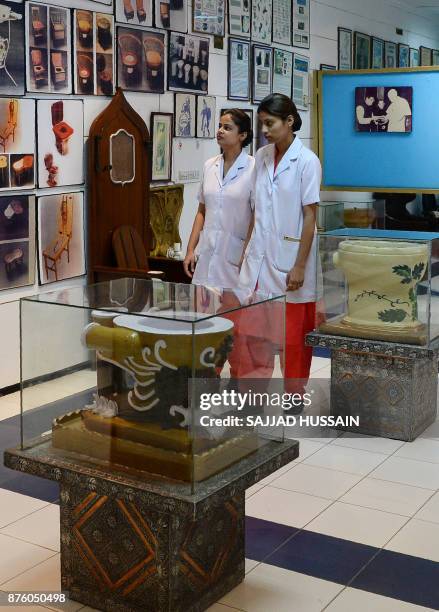 In this photograph taken on November 15 nursing students walk through the Sulabh International Museum of Toilets in New Delhi. A throne with a...