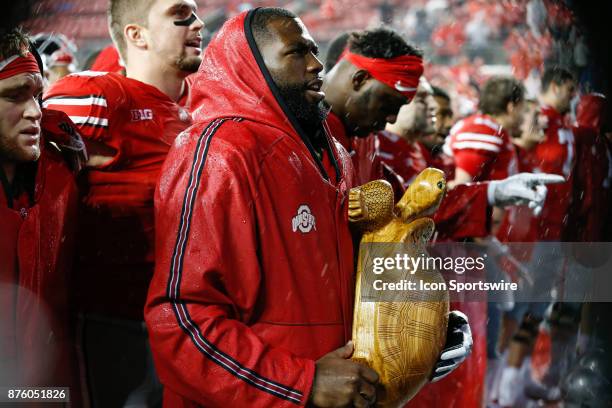 Ohio State Buckeyes quarterback J.T. Barrett holds the Illibuck Trophy while the team sings Carmen Ohio at the conclusion of the game between the...