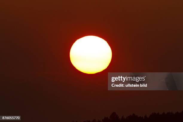 Sonnenuntergang gelbliche Sonne vor roetlichem Abendhimmel mit Wolken