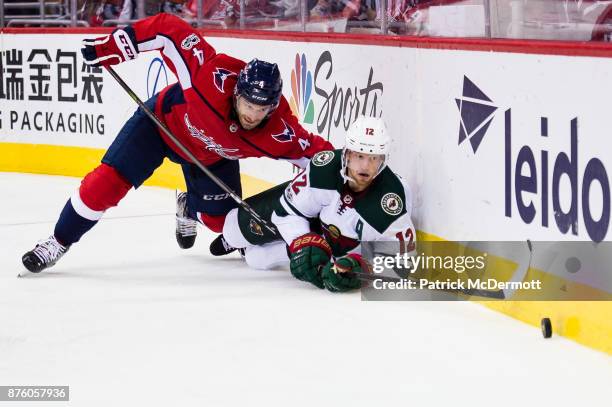 Taylor Chorney of the Washington Capitals and Eric Staal of the Minnesota Wild battle for the puck in the second period at Capital One Arena on...