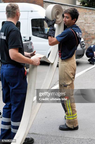 Feuerwehrmänner der Feuerwache 1300 in Berlin-Prenzlauer Berg wickeln gemeinsam einen Schlauch auf