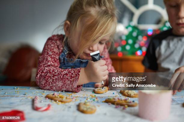 siblings decorating gingerbread men - holiday preparation stock pictures, royalty-free photos & images