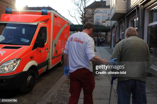 Sanitäter der Berliner Feuerwehr begleitet einen Patienten zum wartenden Rettungswagen