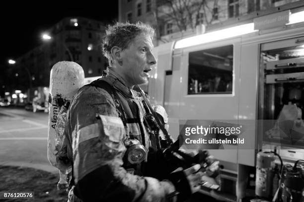Erschöpfter Feuerwehrmann beim Ablegen des Atemschutzgeräts nach dem ersten Löschangriff - Löscharbeiten während eines Dachstuhlbrandes in der...