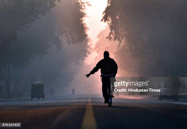 Man cycles, early morning after late night drizzling helped to lower the smog and pollution level, at Crescent road, on November 18, 2017 in New...