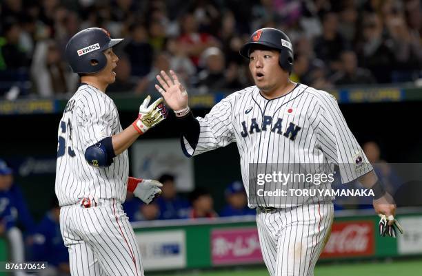 Japanese infielder Hotaka Yamakawa is congratulated by his teammate Ryoma Nishikawa after crossing the home plate following a single hit by infielder...