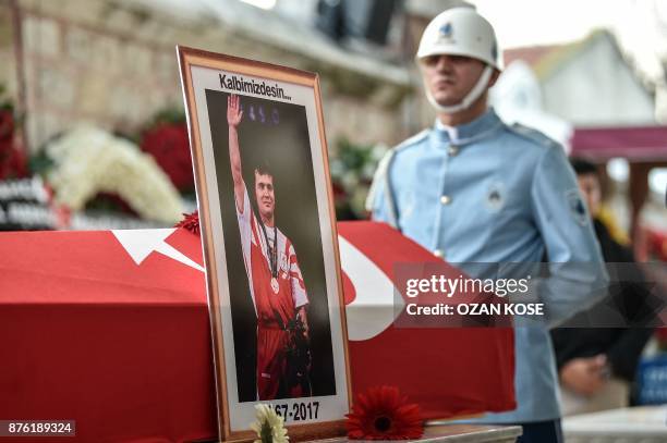 Police officer stays next to a coffin of Turkey's legendary triple Olympic gold-medal winning weightlifter Naim Suleymanoglu on November 19, 2017...