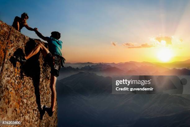 teamwork paar klimmen helpende hand - red couple stockfoto's en -beelden