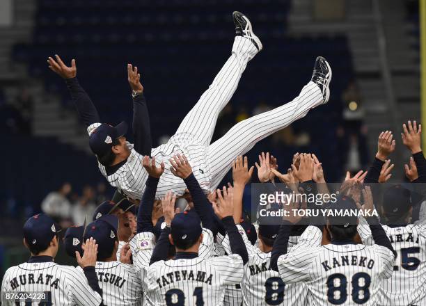 Japanese players tosses their playing manager Atsunori Inaba into the air to celebrate their victory after the final match against South Koreea in...