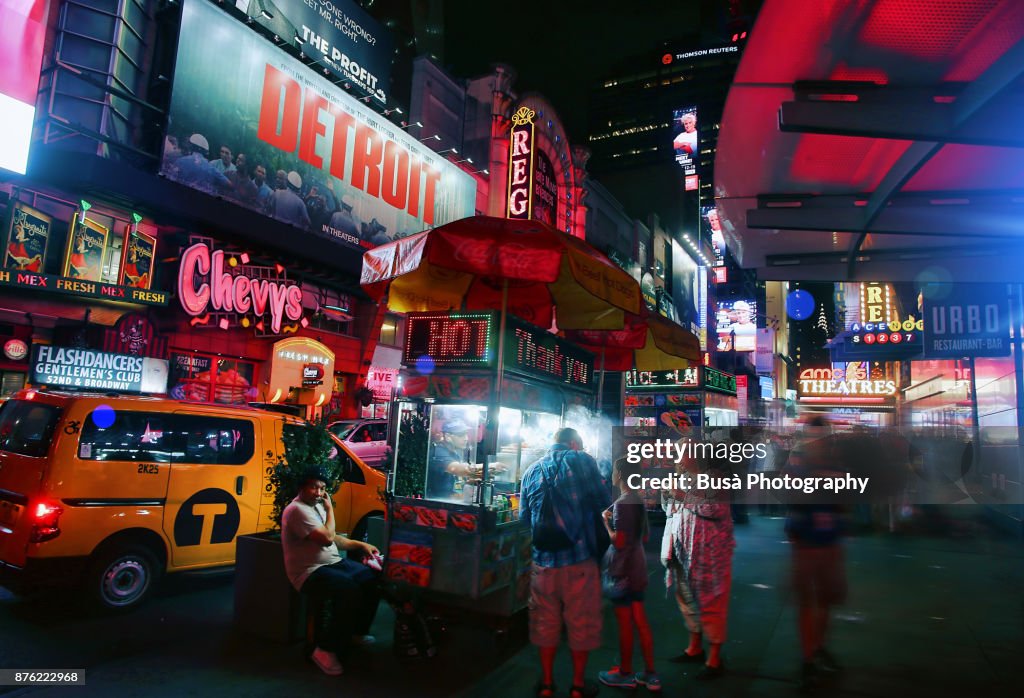 Night street scene in Midtown Manhattan: food cart vendor and marquee of theater along 42nd Street. New York City, USA