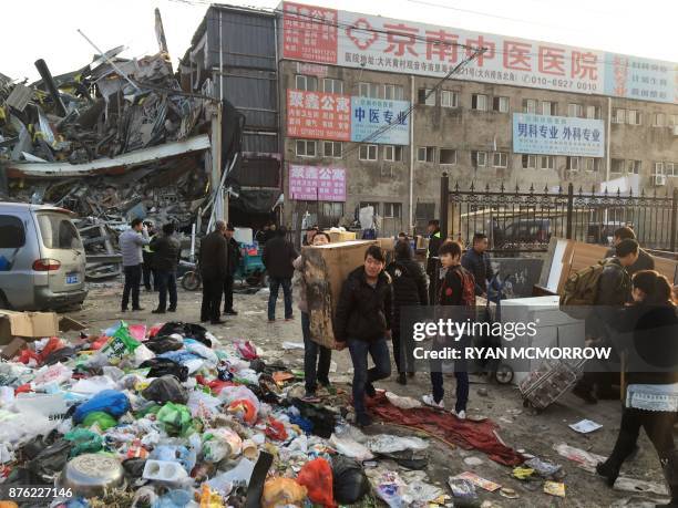 Residents carrying their belongings evacuate the site of a fatal housing block fire in Beijing on November 19, 2017. Chinese authorities on November...