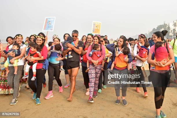 Actor and model Milind Soman and Women with their babies participate in Baby-Wearing Super Moms event organised by by Colors Pinkathon at Juhu Beach,...