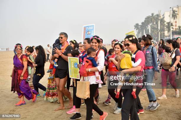 Actor and model Milind Soman and Women with their babies participate in Baby-Wearing Super Moms event organised by by Colors Pinkathon at Juhu Beach,...