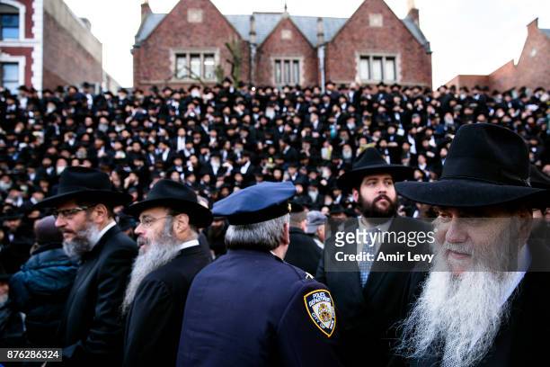 Police officer walks through the crowd as Hasidic rabbis prepare to pose a group photo, part of the annual International Conference of...