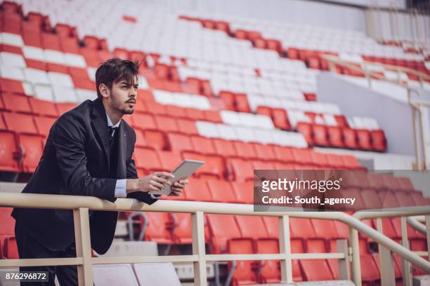 mann mit touchpad auf stadion - leadership in coaching stock-fotos und bilder